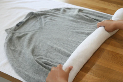 Wool jumper placed on towel being rolled up